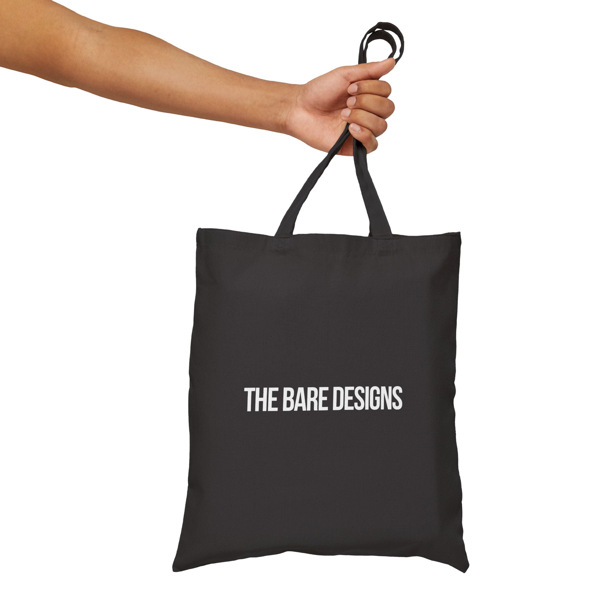 Black tote bag with 'THE BARE DESIGNS' text held by a hand on a white background