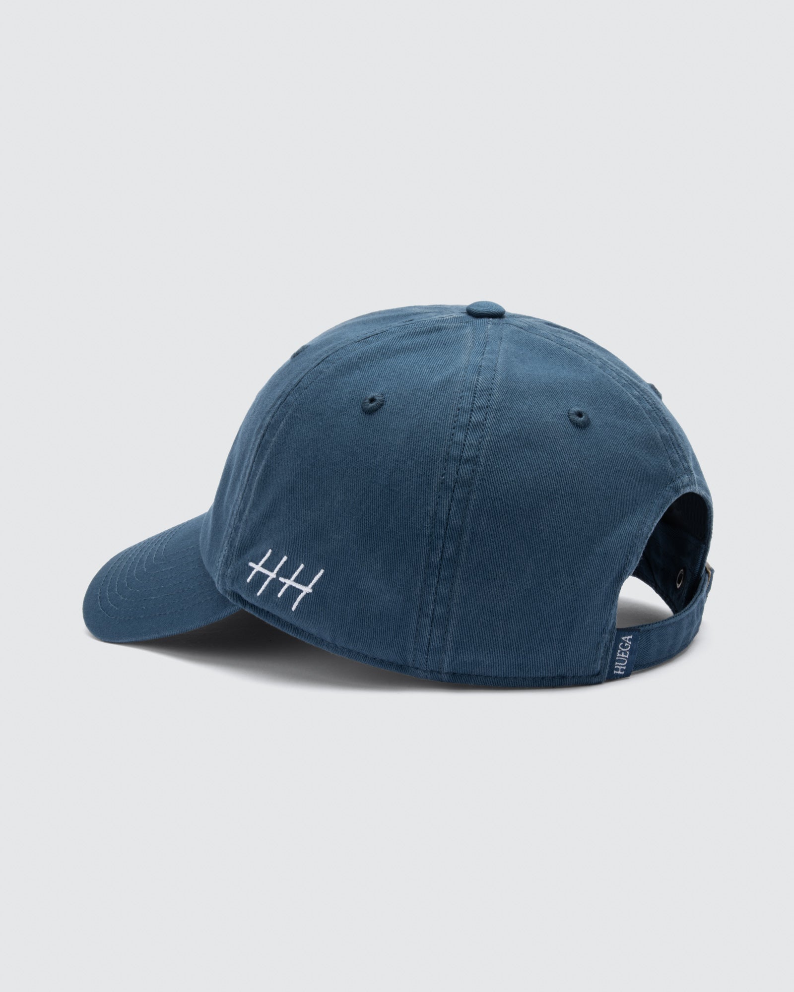 Blue cap with a small logo on the back against a light gray background.  Varsity | Washed Slate Blue Cap by Huega House