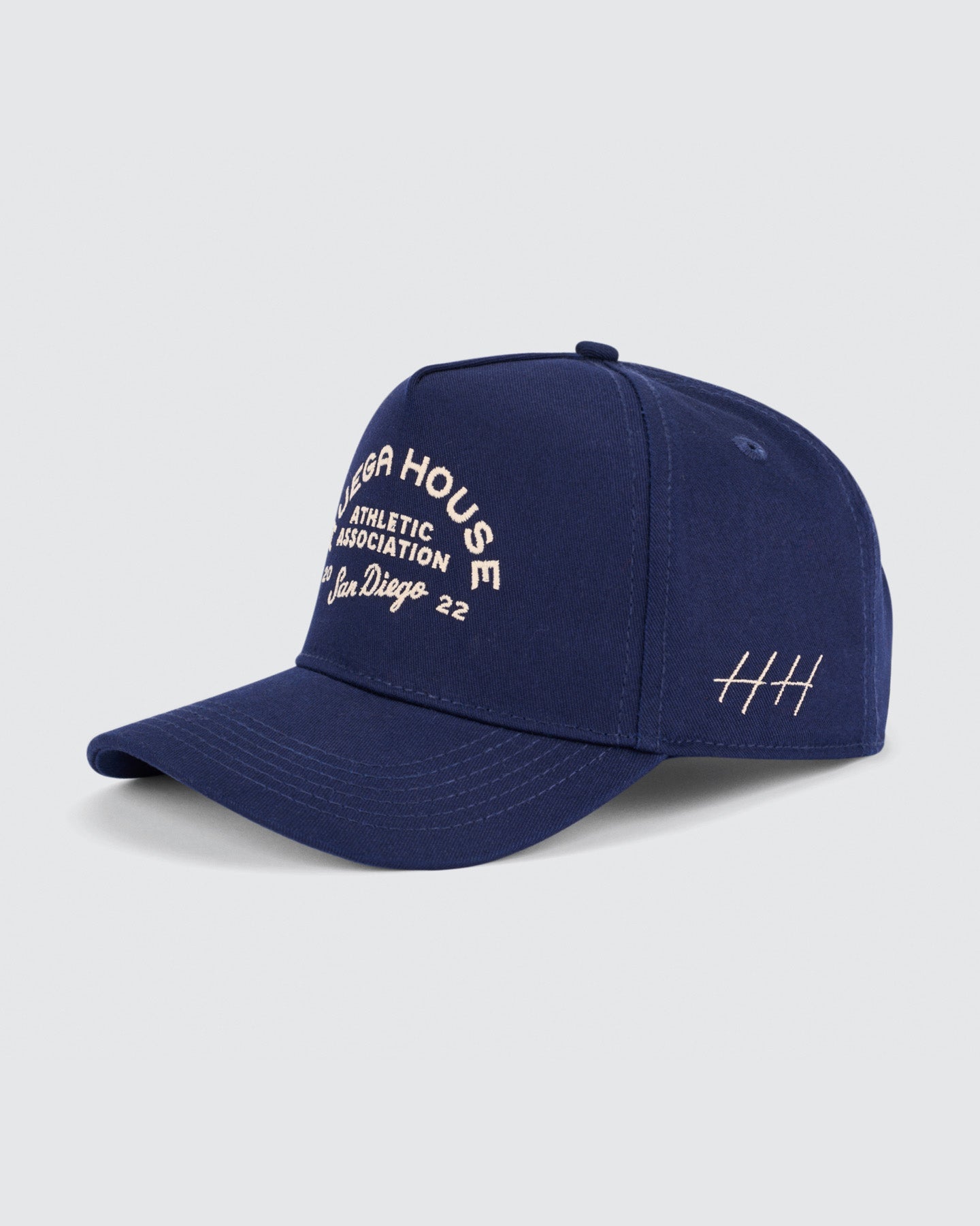 Navy blue cap with white text on a light gray background | Huega House