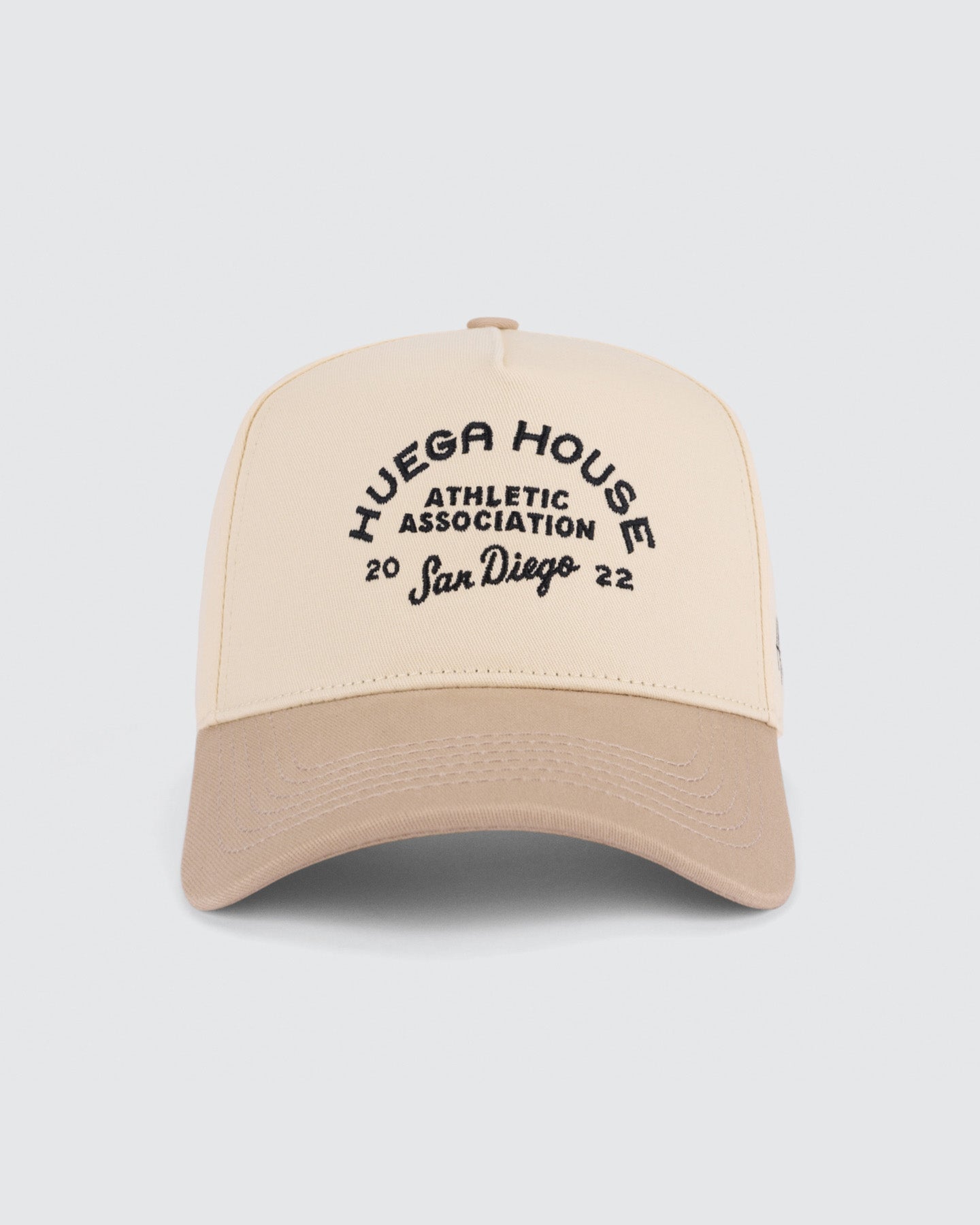Beige and brown cap with 'Huega House Athletic Association San Diego' text on a white background